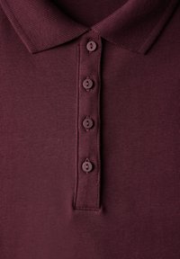 Vinröd polo-shirt med en texturerad krage, fem matchande knappar och ett jämnt stickat tyg.