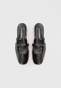 Črne usnjene slingback čevlje s kvadratnimi prsti in širokim trakom čez stopalo. Imajo gladko površino in minimalističen dizajn.