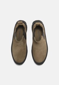 Bruna mockakängor i slip-on-modell med svarta elastiska sidodetaljer och en gummisula. Har en slät textur och rund tådesign.