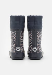Par de botas de lluvia azul marino con pequeños patrones florales en rosa y blanco y puños acolchados, vistas desde atrás contra un fondo blanco.