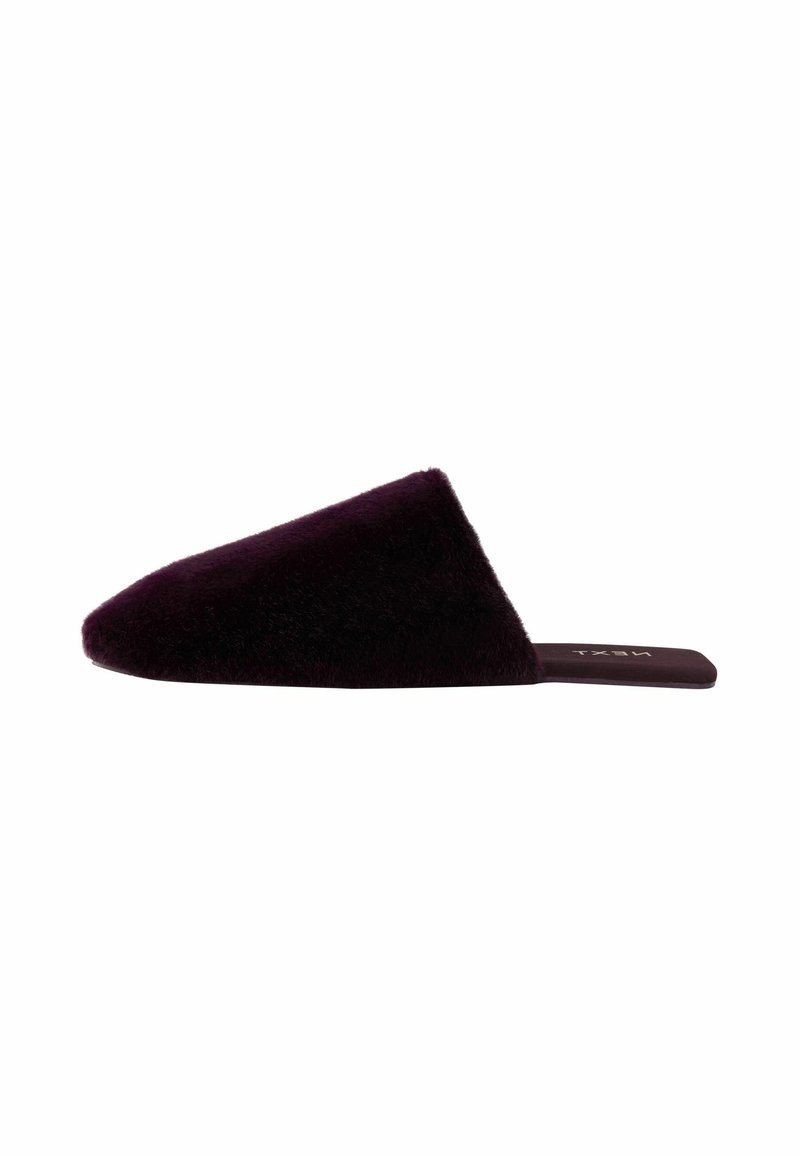Faux fur slide slipper in deep purple with a pointed, asymmetrical upper. Flat sole with subtle branding on the insole. Soft texture.