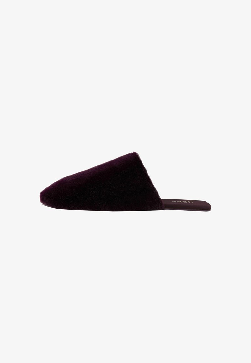 Faux fur slide slipper in deep purple with a pointed, asymmetrical upper. Flat sole with subtle branding on the insole. Soft texture.