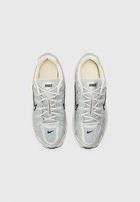 Παπούτσια τρεξίματος Nike σε ανοιχτό γκρι πλέγμα με μαύρες λεπτομέρειες. Διαθέτουν σχέδιο με κορδόνια, επενδυμένο κολάρο και ορατή επωνυμία στη γλώσσα.