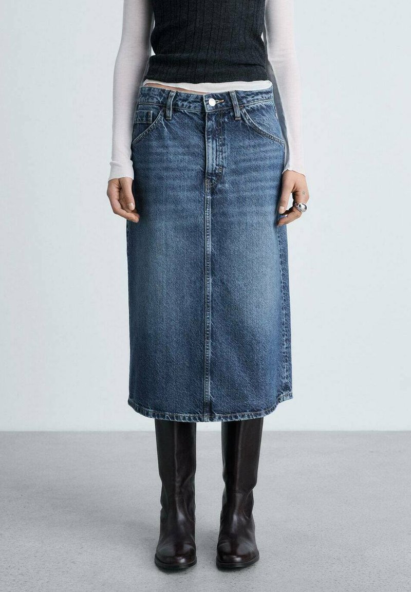 Blauwe denim rok tot de knie met een rechte snit, voorzien van een voornaad en klassieke vijfzakkenstijl, gedragen met hoge bruine laarzen.