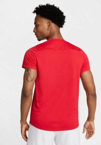Rød trenings T-skjorte med korte ermer, laget av glatt, lett stoff. Har et enkelt design og en rett hem.