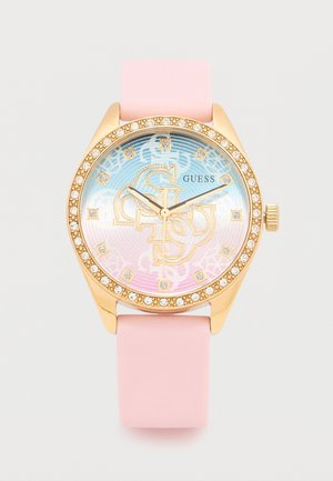 Guess armbåndsur i guldfarve med pink silikonerem, krystaller på bezelen og iriserende urskive med dekorative logoer og krystal-timemarkører.