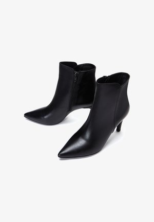 Bottines en cuir noir avec des pointes effilées et une fermeture éclair sur le côté. Présente une silhouette élégante et un talon aiguille de 5 à 7,5 cm. Texture lisse.