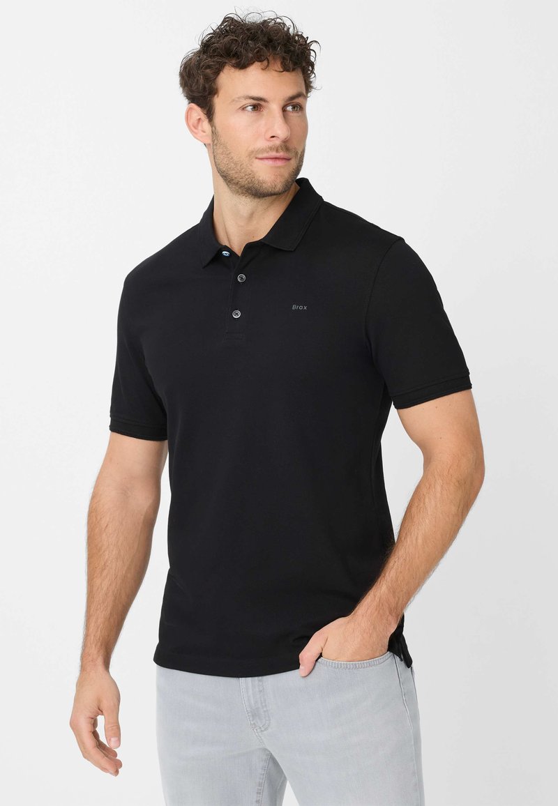 Zwarte polo shirt van zacht materiaal, met een klassieke kraag, drie knopen bij de hals en subtiele branding aan de voorkant.