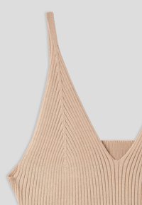 Top a costine con scollatura a v in un morbido colore beige. Realizzato in un materiale knit elasticizzato, con spalline sottili e un design aderente.