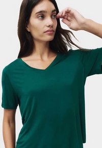 Donkergroen T-shirt met V-hals en korte mouwen, gemaakt van zachte stof, met een losse pasvorm, een gladde textuur en zonder zichtbare patronen of accenten.