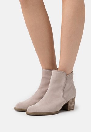 Bottines en daim gris clair avec un bout rond et un talon empilé, présentant une finition lisse et des détails de couture subtils.