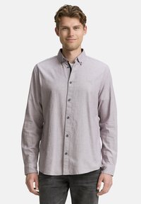 Chemise boutonnée lilas clair avec une finition texturée, un col et des accents de boutons noirs, associée à un pantalon gris foncé.