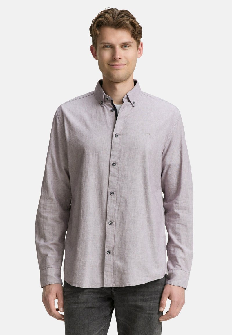 Chemise boutonnée lilas clair avec une finition texturée, un col et des accents de boutons noirs, associée à un pantalon gris foncé.