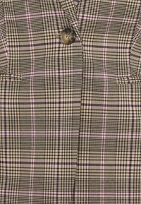 Geruite blazer met een beige, zwarte en roze patroon, een enkele bruine knoop en twee voorzakken met een gestructureerde stof.