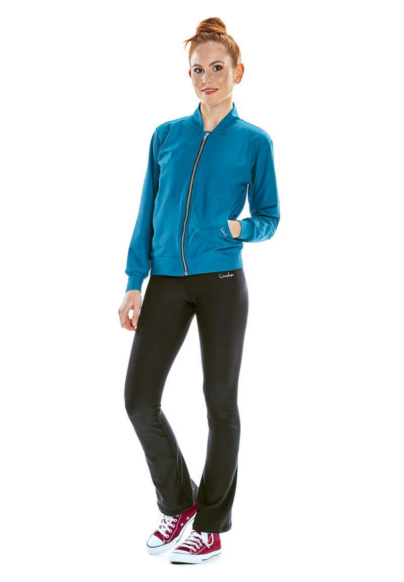 Teal zip-up jacka med ståkrage, kombinerad med svarta leggings och röda sneakers. Slät tyg och figurnära design för aktiv användning.