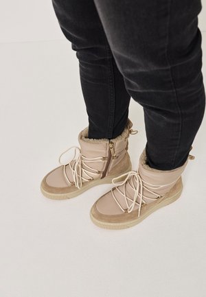Beige snørebånd ankelstøvler med en polstret overdel, faux fur-foring og gummisåler. Lynlåse på siden og strukturerede detaljer på hælen.
