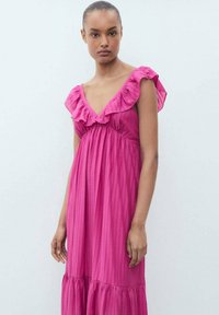 Fuksia mekko, jossa on röyhelöinen V-pääntie ja lyhyet hihat, sisältää pystysuoran ribbitekstuuri ja kerroksellisen helman.