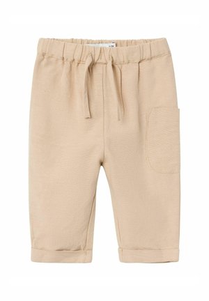 Pantalons en coton beige avec une taille élastique, cordon de serrage et une poche latérale. Présente des ourlets roulés et un tissu texturé.