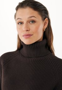 Suéter marrón de punto con canalé, cuello alto y mangas raglán, que presenta un patrón texturizado y un acabado suave.