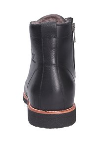 Stivale alla caviglia in pelle nera con una finitura testurizzata, cerniera laterale e suola in gomma. Presenta un accentuazione marrone attorno alla suola. Fodera liscia visibile nella parte superiore.