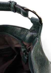 Groene leren handtas met een gestructureerd oppervlak, met een donkerbruine stoffen binnenkant en een ritsvak. Inclusief een gestructureerd handvat.