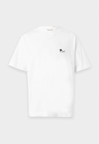 T-shirt blanc à manches courtes avec un petit trèfle noir et le mot "loved" imprimé sur la poitrine gauche.