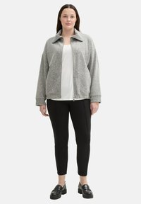 Harmaa vetoketjullinen takki, jossa on kaulus, teksturoitua kangasta, sivutaskut, yhdistetty mustiin slim fit -housuihin ja mustiin loafer-kengiin.