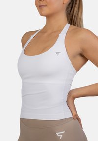 Bela atletska majica bez rukava z okroglim izrezom in tankimi naramnicami, ki na strani vsebuje subtilen logotip ter prilegajočo zasnovo za udobje.