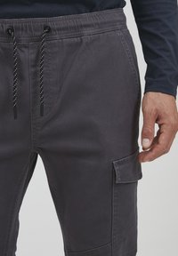 Grijze cargobroek van een katoenmix, met een rekbare tailleband met een trekkoord, zijzak en stiksels.