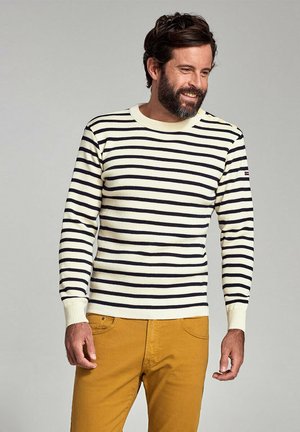 Beige og marineblå stribet sweater med lange ærmer, ribbet neckline og cuffs, parret med sennepsfarvede bukser. Struktureret strikstof.