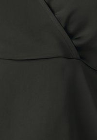 Tessuto nero con una superficie liscia e una sottile lucentezza. Presenta cuciture diagonali e un dettaglio plissettato, creando morbide pieghe nel materiale.