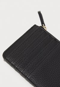 Cartera de cuero negra con superficie texturizada, múltiples ranuras para tarjetas y cierre de cremallera. Incluye un lazo para acoplar un llavero o correa.