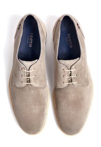 Chaussures en daim beige avec un design à lacets, bouts arrondis et semelles en caoutchouc de couleur claire contrastante. L'intérieur présente une doublure bleu foncé.