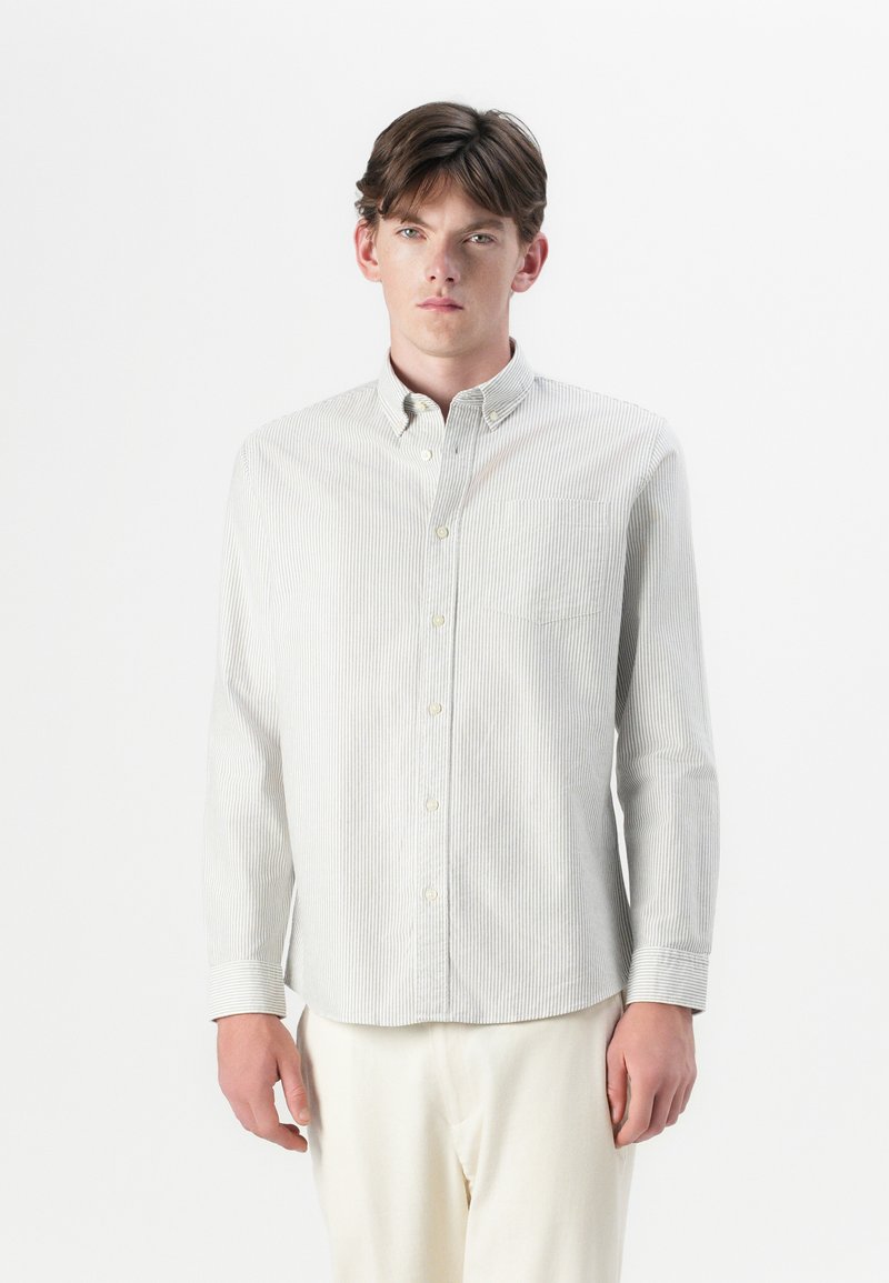 Camisa de botones a rayas claras con cuello, que cuenta con un solo bolsillo en el pecho, mangas largas y un corte relajado. Tejido de algodón suave.