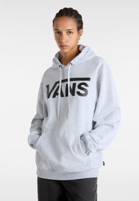 Felpa grigia in pile con grande logo nero "VANS", cappuccio con cordini e tasca frontale. Il tessuto appare morbido e textured.