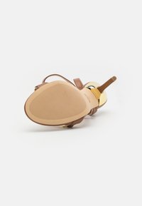 Sandal con tacco marrone caratterizzato da una tomaia in pelle liscia, dettagli in tonalità oro, una sottile cinghia alla caviglia e una suola in gomma testurizzata.