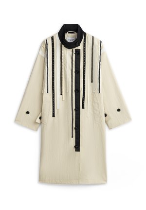 Langer cremefarbener Mantel mit schwarzem hohem Kragen, schwarzen vertikalen Streifen, dekorativen Bändern und vorderer Knopfleiste.