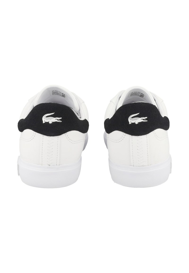 Hvide sneakers med sort ruskindsdetalje ved hælen. Har en tekstureret overdel, rund tå og hvid gummisål. Lacoste-logo på hælen.