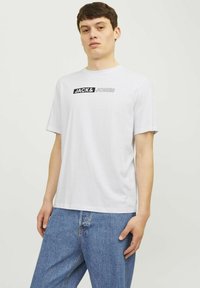 Witte katoenen t-shirt met korte mouwen, voorzien van het "JACK & JONES" logo in zwarte print over de borst. Casual fit en een gladde textuur.
