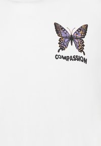 Weißes Baumwoll-T-Shirt mit einem lila und orangefarbenen Schmetterlingsmotiv und dem Text "MITGEFÜHL" darunter. Kurzarm-Design, glatte Textur.