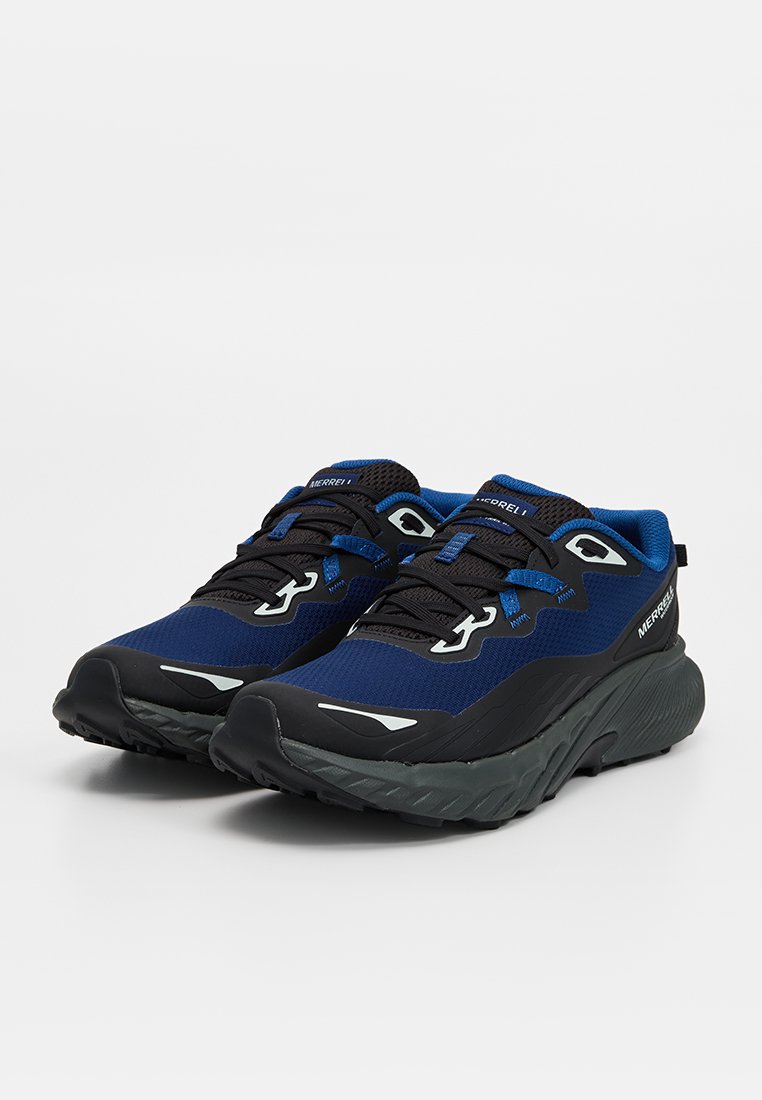 Paire de chaussures de trail Merrell bleu et noir avec semelles épaisses et texturées et lacets noirs sur fond blanc.