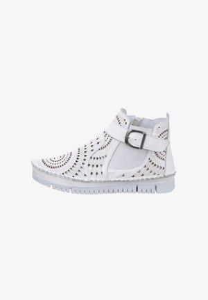 White ankle boot with cut-out detailing, textured surface, adjustable buckle strap, and a thick white rubber sole.