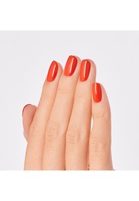 Röd glansig nagellack på fem välskötta fingrar, som visar en jämn finish och oval form. Bakgrunden är helt vit.