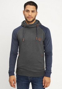 Sudadera con capucha en gris con mangas raglán en azul marino. Cuenta con cordones, detalles de cuero y una tela texturizada. Diseño ajustado.