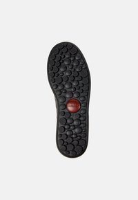 Black rubber shoe sole with circular and textured patterns; features a red circular accent labeled "Camper" and size "42."