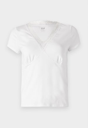 Camiseta blanca de manga corta con escote en V, adornada con encaje en el borde del escote y sutil fruncido en el busto. Material de algodón suave.