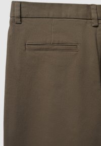 Braune maßgeschneiderte Hosen aus einem glatten, strukturierten Stoff mit einer Gesäßtasche. Der Bund verfügt über Gürtelschlaufen für zusätzliche Funktionalität.