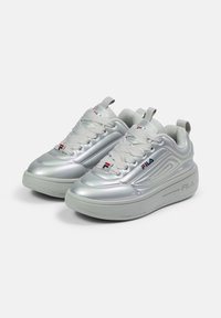 Sneaker atletici argentati con una texture lucida e liscia, dotati di una suola spessa e cuciture dettagliate. Inclusi lacci e accenti di branding.