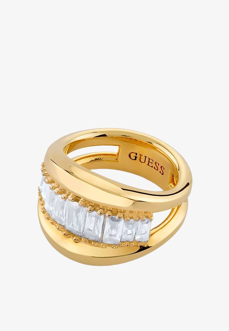 Bague ton or avec des pierres rectangulaires transparentes alignées et le mot "GUESS" gravé à l’intérieur de l’anneau.
