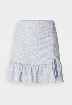 Jupe mini bleu clair avec un motif floral, détail de côté froncé et ourlet volanté. Tissu texturé avec des accents à cordon.